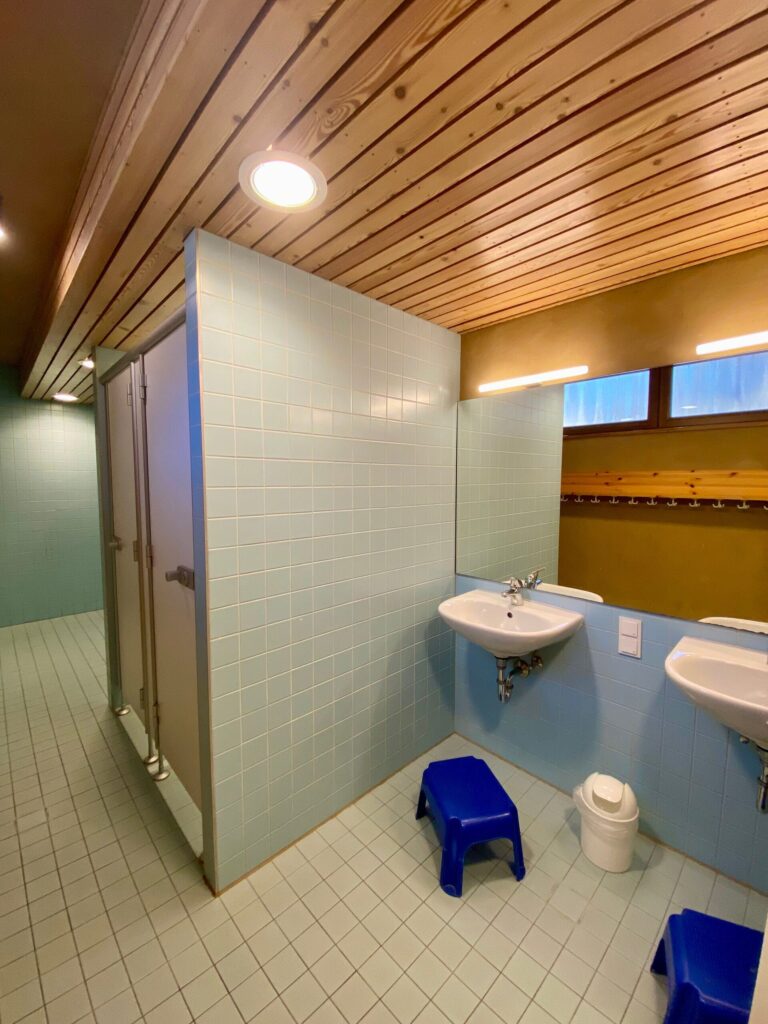 Bad mit Waschbecken und Toilettenkabinen im Langhaus.